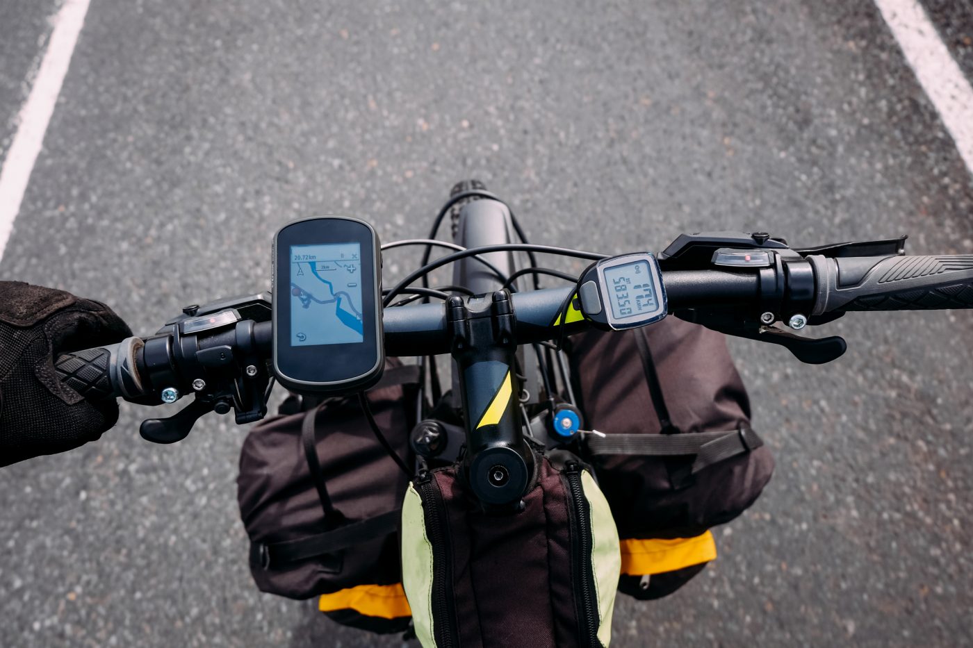 Bikepackingstyre ovanifrån med en GPS-cykeldator som visar en karta och en trådlös cykeldator som visar fart