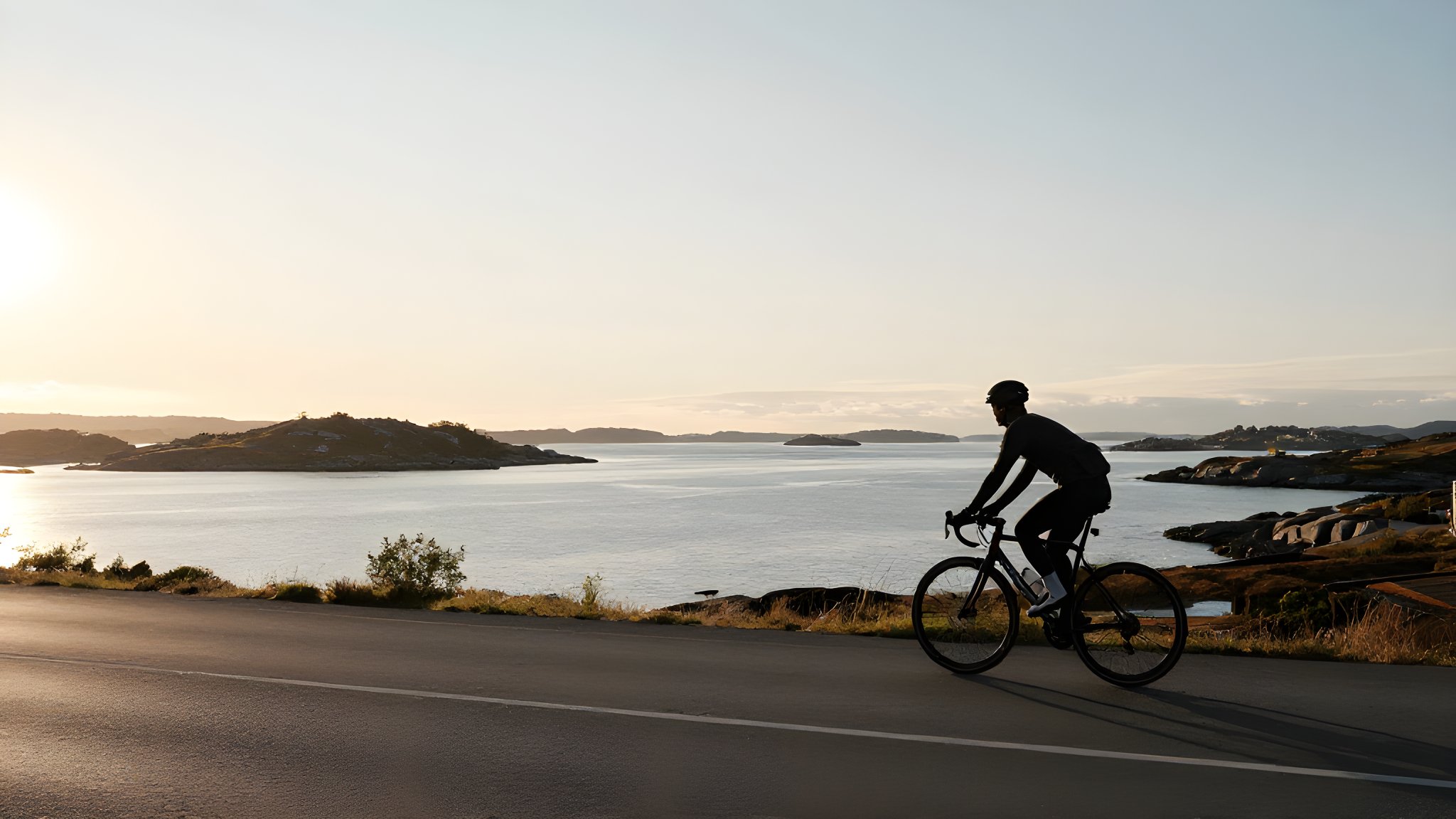 Stämningsbild: cyklist i silhuett längs kustväg vid solnedgång